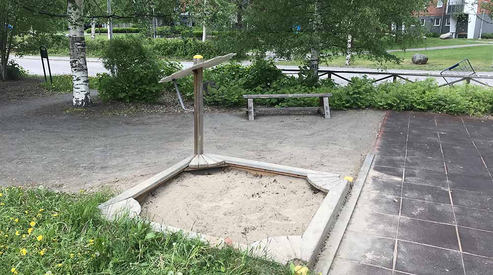 Lekyta med sand med stilistisk blomma i ena hörnet