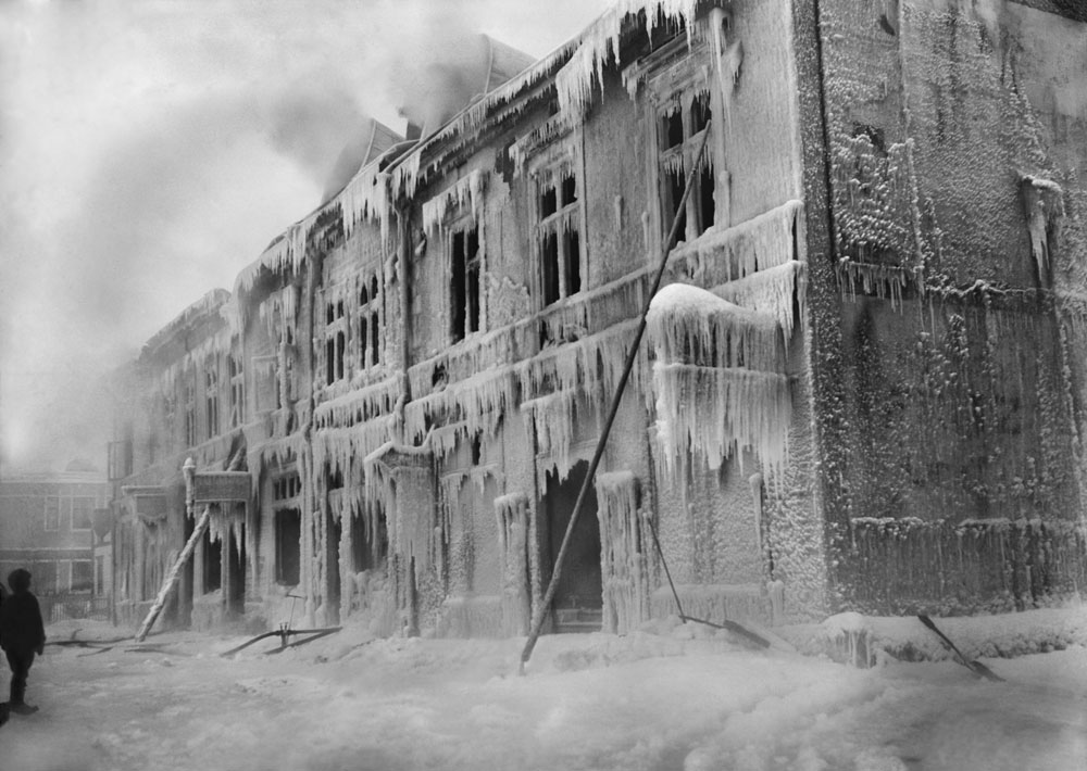 Utbrunnet hus, täckt av is och istappar efter brandkårens släckning.
