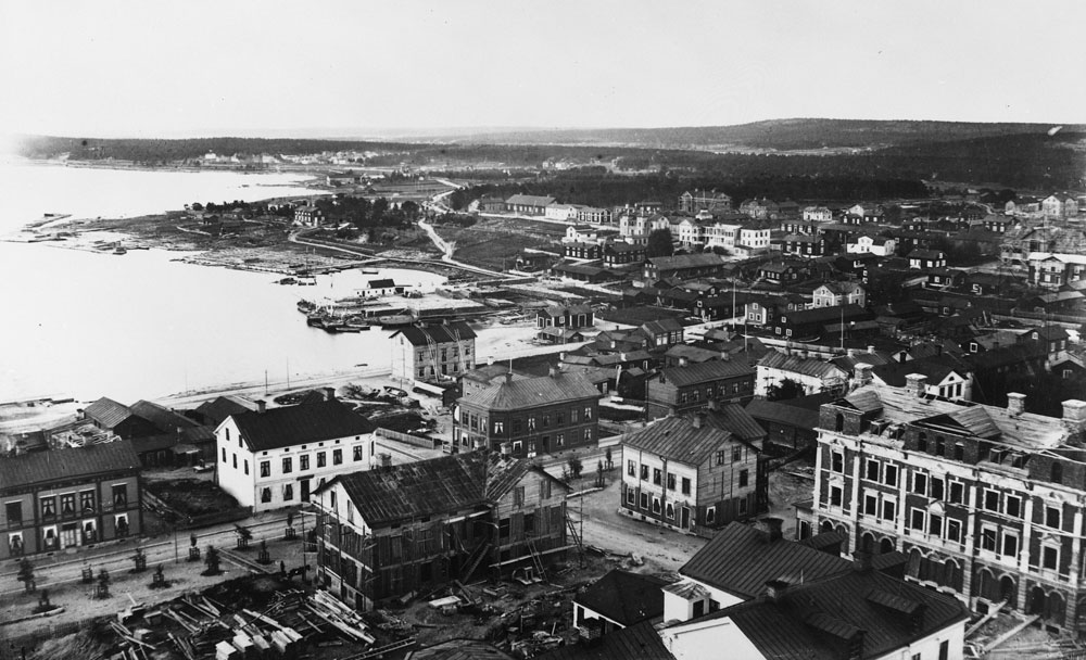 Foto mot Norra Hamn på 1890-talet. Trähus i staden och i fjärran berg och skog.